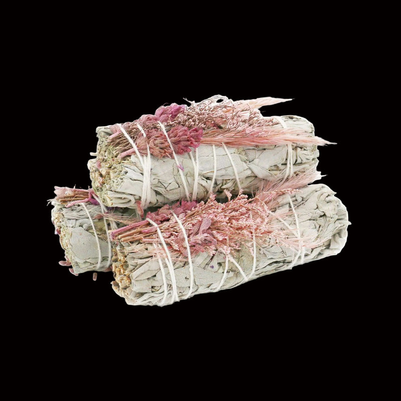 Three bundles of white and pink sage tied together on a white background