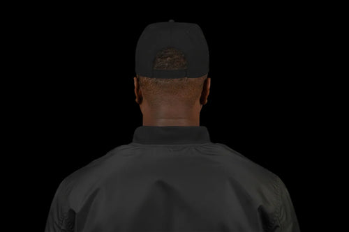 Person wearing a black cap and green shirt on a white background