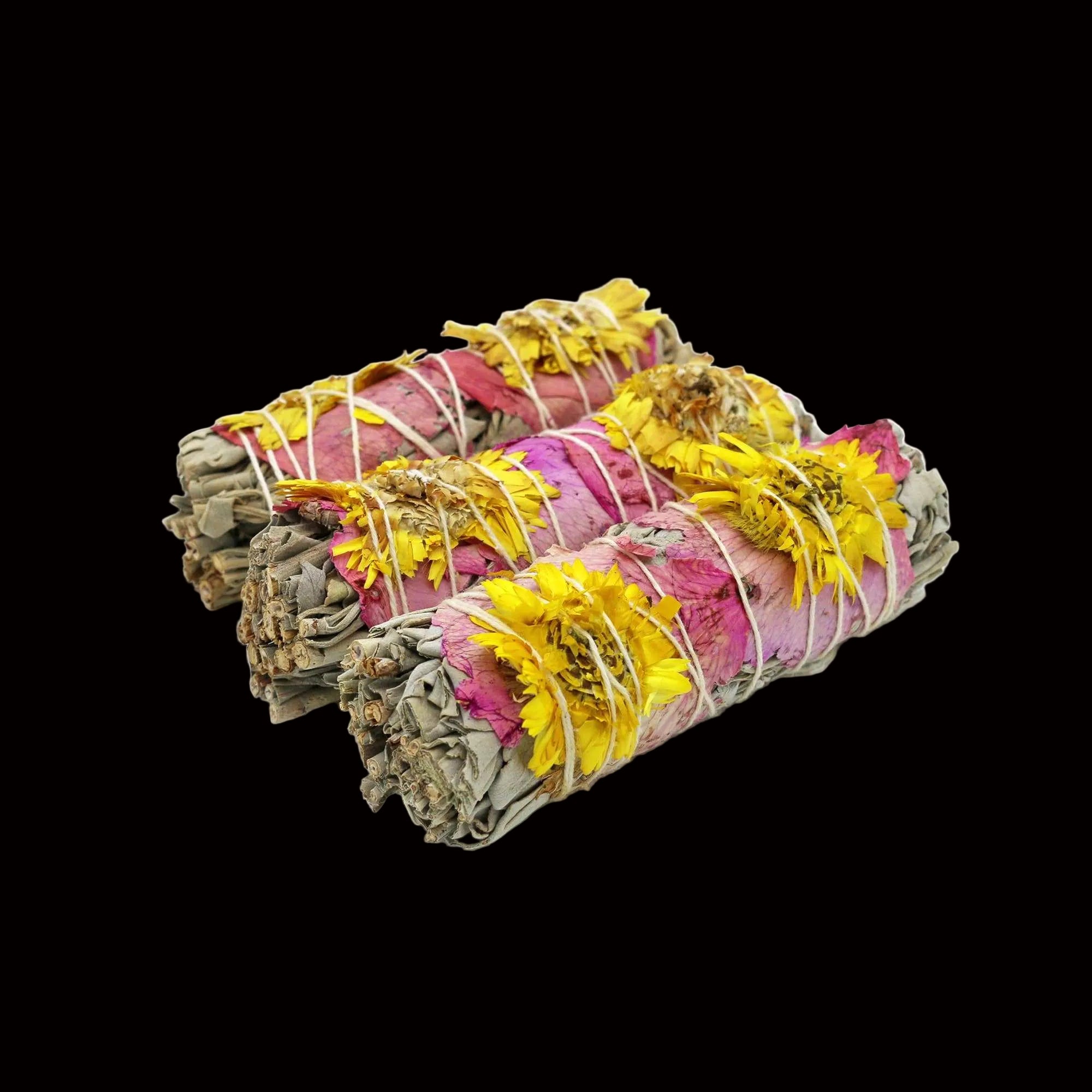 Three bundles of sage and rose smudge sticks on a white background
