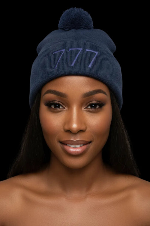 Navy blue beanie with pom-pom and '777' logo on a white background