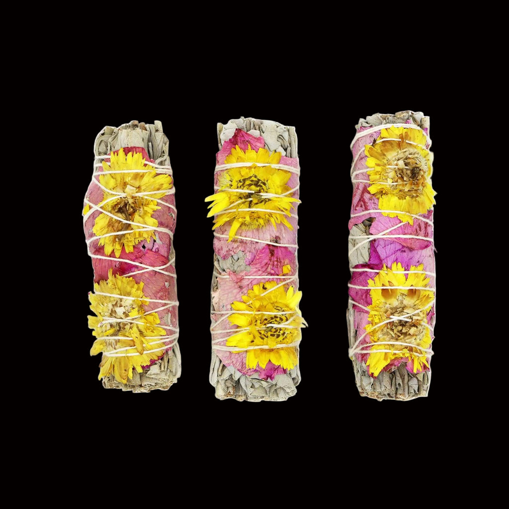 Three bundles of dried flowers and herbs tied together on a white background