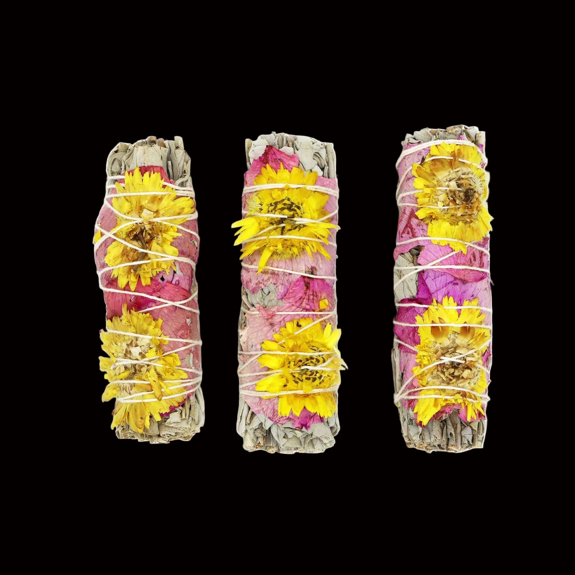 Three bundles of dried flowers and herbs tied together on a white background