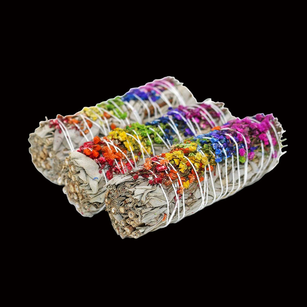 Three bundles of sage with colorful flowers tied together on a white background