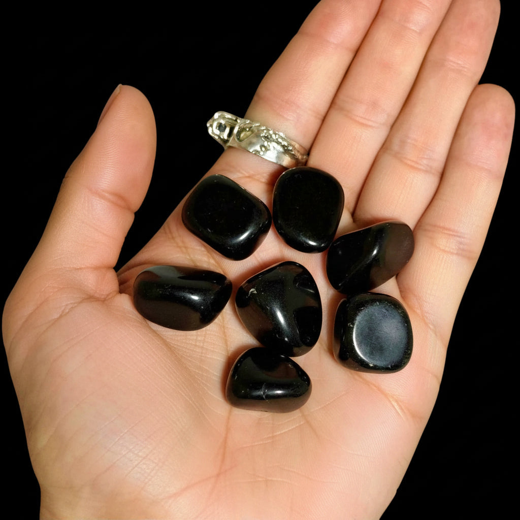 Black stones on a black background with a hand and ring visible