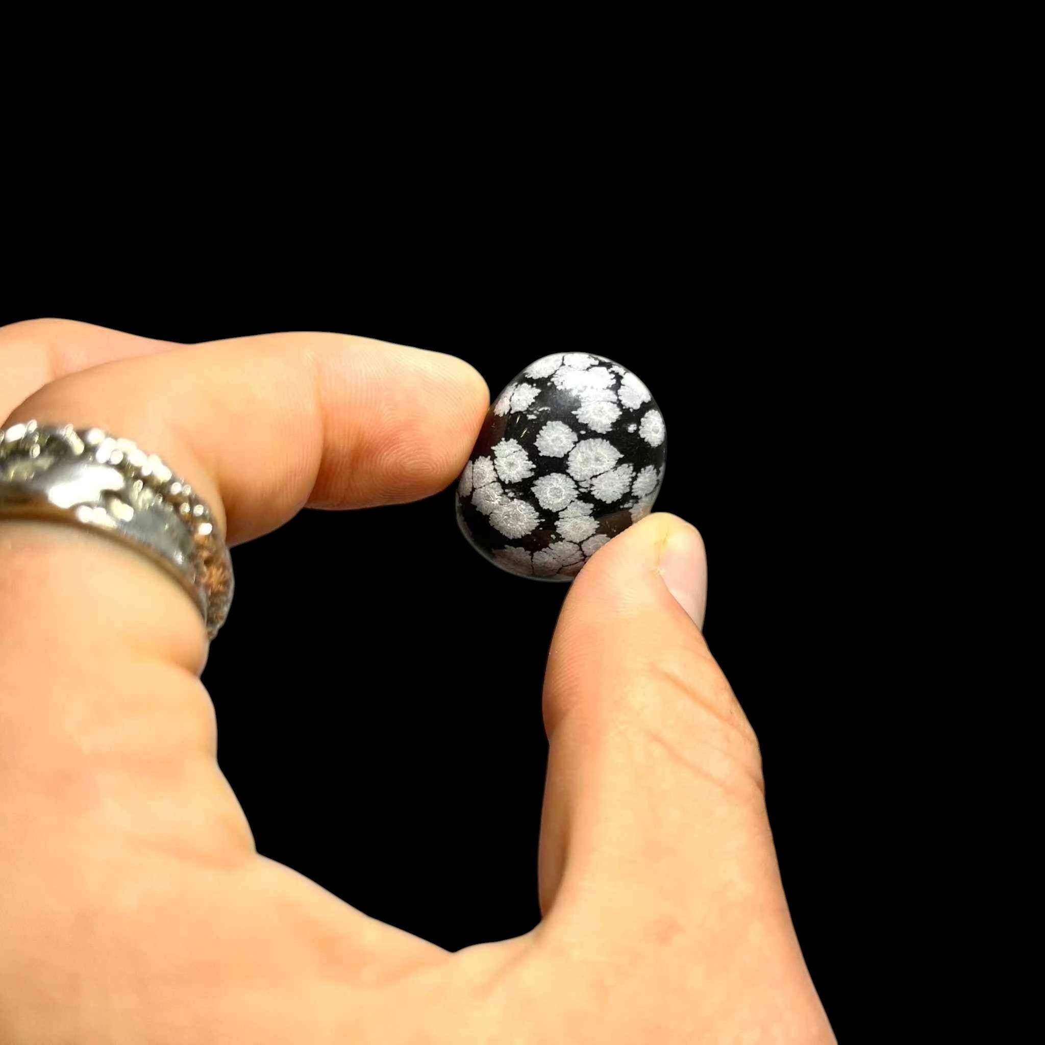 Hand holding a black and white patterned ball against a black background