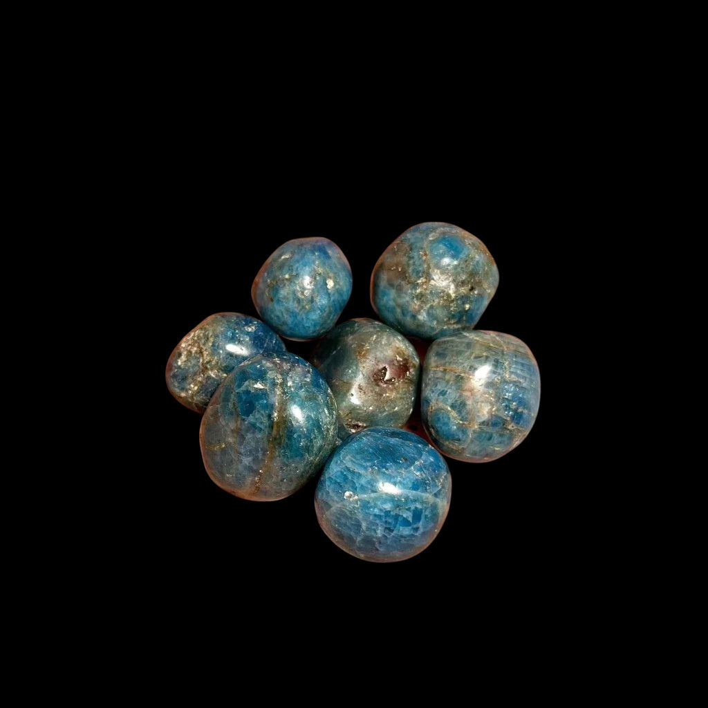 Blue stone beads on a black background with a hand reaching towards them.