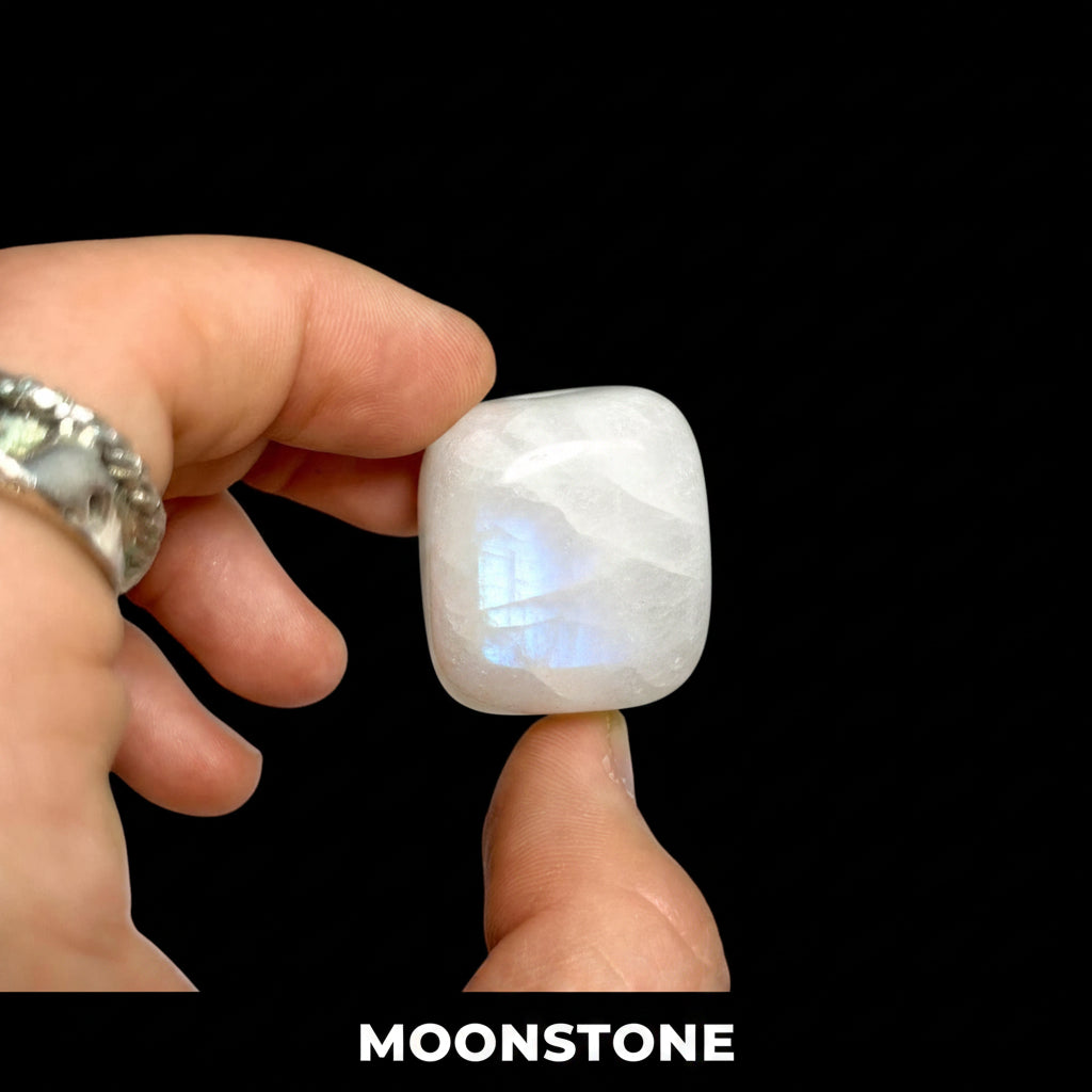 Hand holding a white stone against a black background