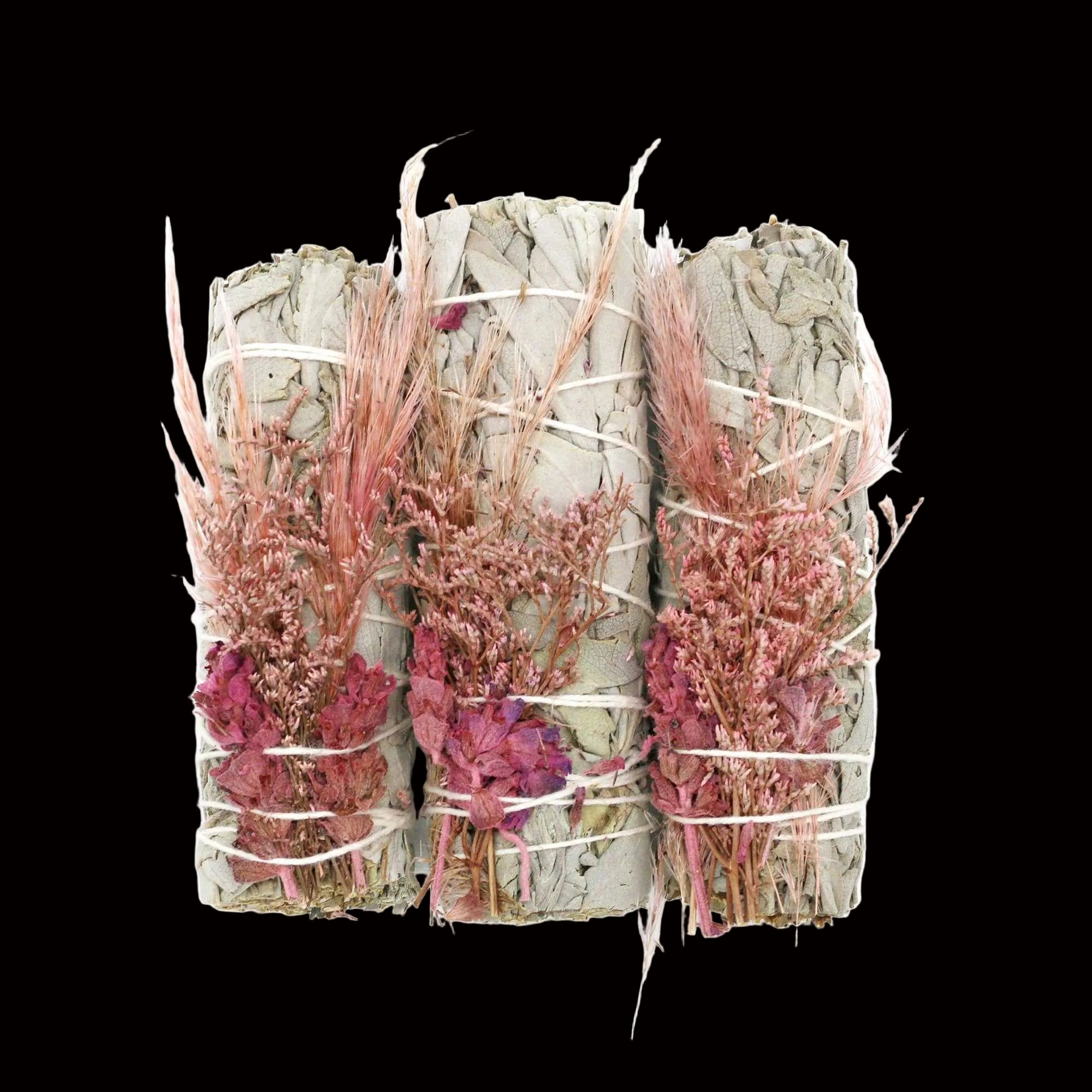 Three bundles of dried herbs tied together with twine on a white background