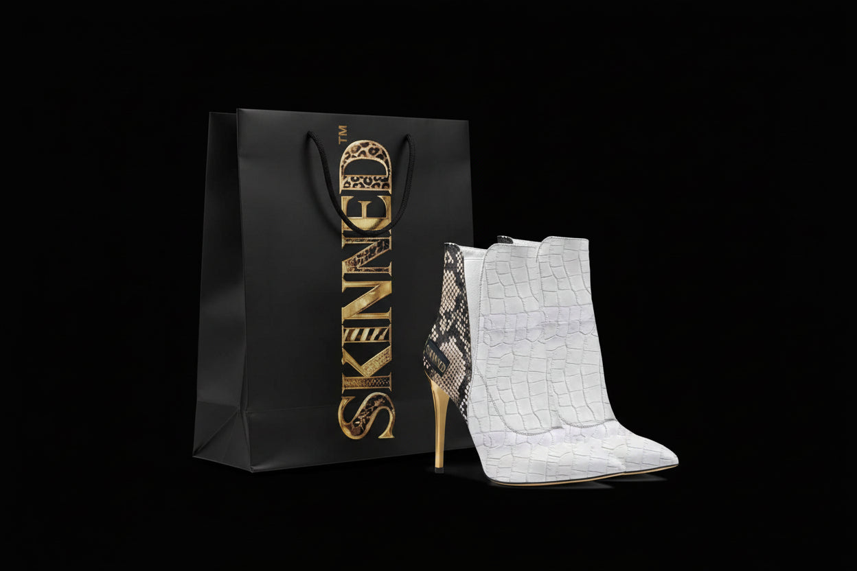 White high-heeled boots with snake print detail next to a black box with 'SKINNED' branding.